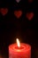 Single wax flame candlelight in dark romantic light on hearts background, love dating, Valentine`s day