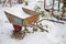 Single wheel rusty wheelbarrow covered by fisrt winter snow. Agriculture concept