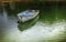 Single white and blue wooden rowboat floating at a buoy on vivid green water