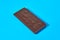 Single whole dark porous chocolate bar lies on blue table on kitchen