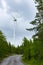 Single Wind Turbine in the middle of the green forest under blue sky with clouds. Windfarm, wind power plant