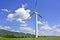 A single windmill in the  foreground against a blue   sky with white clouds