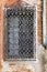 Single window with rusted metal bars on an old semi-destroyed brick wall in Venice, Italy