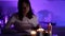 Single woman is drinking tea and reading book at home at night, romantic candle light