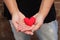 A single woman with her hands together holding a red felted heart