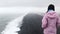 Single woman tourist stand thoughtful look at atlantic ocean waves. Famous iconic cliff viewpoint over Reynisfjara black sand