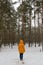 Single woman in yellow jacket walking in frozen snowy forest