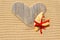 Single wooden love heart and seashell in the sand