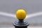 Single yellow metal ball on street post, blurred street