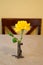 Single yellow rose in a tiny silver ornate vase in a yellow room