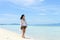 single young Asian girl walking on tropical white sand beach,