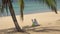 Single young woman enjoys the holiday under a palm tree on the exotic beach