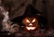 Sinister glowing Halloween pumpkin in smoke, cobweb in the background of burlap