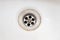 A sink drain hole with limescale or lime scale and rust on it, dirty rusty bathroom washbowl