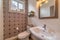 Sink toilet and mirror inside residential bathroom with decorative accent wall