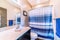 Sink on vanity area beside toilet and blue striped curtain of shower and bathtub