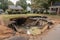 a sinkhole in a residential neighborhood, with pieces of broken furniture and debris visible inside