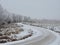 Sinuous road, trees and field in winter frost, Lithuania