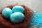 Sisal nest with painted Easter eggs on color background, closeup.