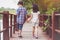 Sister and brother hand in hand walking together in Wood bridge