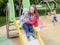 Sister and brother playing on the Playgrou. The girl helps a little boy on a children`s slide.