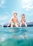 Sister and brother sitting on inflatable mattress and enjoying the sea water, cheerfully laughing when swim in the sea. Careless