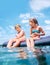 Sister and brother sitting on  inflatable mattress and enjoying the sea water, have fun when swim in the sea. Careless childhood
