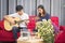 Sister and brother sitting playing guitar, singing To  build up friendship a family. happily In the living room at their home