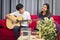 Sister and brother sitting playing guitar, singing To  build up friendship a family. happily In the living room at their home