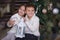 Sister and brother sitting under Christmas tree with gifts