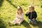 Sister and brother smell flowers on green grass