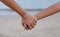 A sister holding her brother\'s hand on the beach