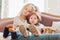 Sister hugs little brother on the couch, focus on legs in warm socks, cozy mood