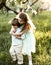 Sister hugs younger brother in the blooming apple orchard