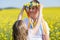 Sister puts on brother Ukrainian wreath with ribbons, against background of fields and sky