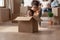 Sister riding younger brother who is sitting in cardboard box