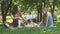 Sisters girls sitting on a park lawn with theirs fluffy corgi dog