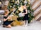 Sisters holding wrapped present beside decorated christmas tree sharing gifts on boxing day