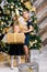 Sisters holding wrapped present standing beside decorated christmas tree at home on boxing day