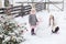 Sisters playing with a snowman with pink knitted scarf