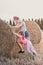 Sisters pushing hay bale playing together outdoors in the countryside