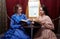 Sisters in retro dress reading books in train compartment