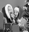 Sisters in Santa hats sit near New Year tree.