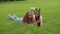 Sisters video conferencing online lying on grass
