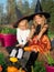 Sisters in witch costumes holding pumpkins with boots
