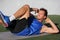 Sit ups - fitness man exercising oblique abs workout with bicycle situps outside in grass in summer. Fit male athlete working out