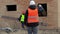 Site manager filmed with tablet PC and worker carries board
