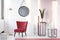 Sitting area with maroon armchair, lamp, mirror, marble cubes an