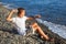 Sitting boy throws stone in sea