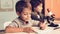 Sitting Boys Using Laptop and Microscope at Home.